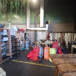 Rekken met tweedehands kleding en uitgestalde tassen en koffers in een kringloopwinkel