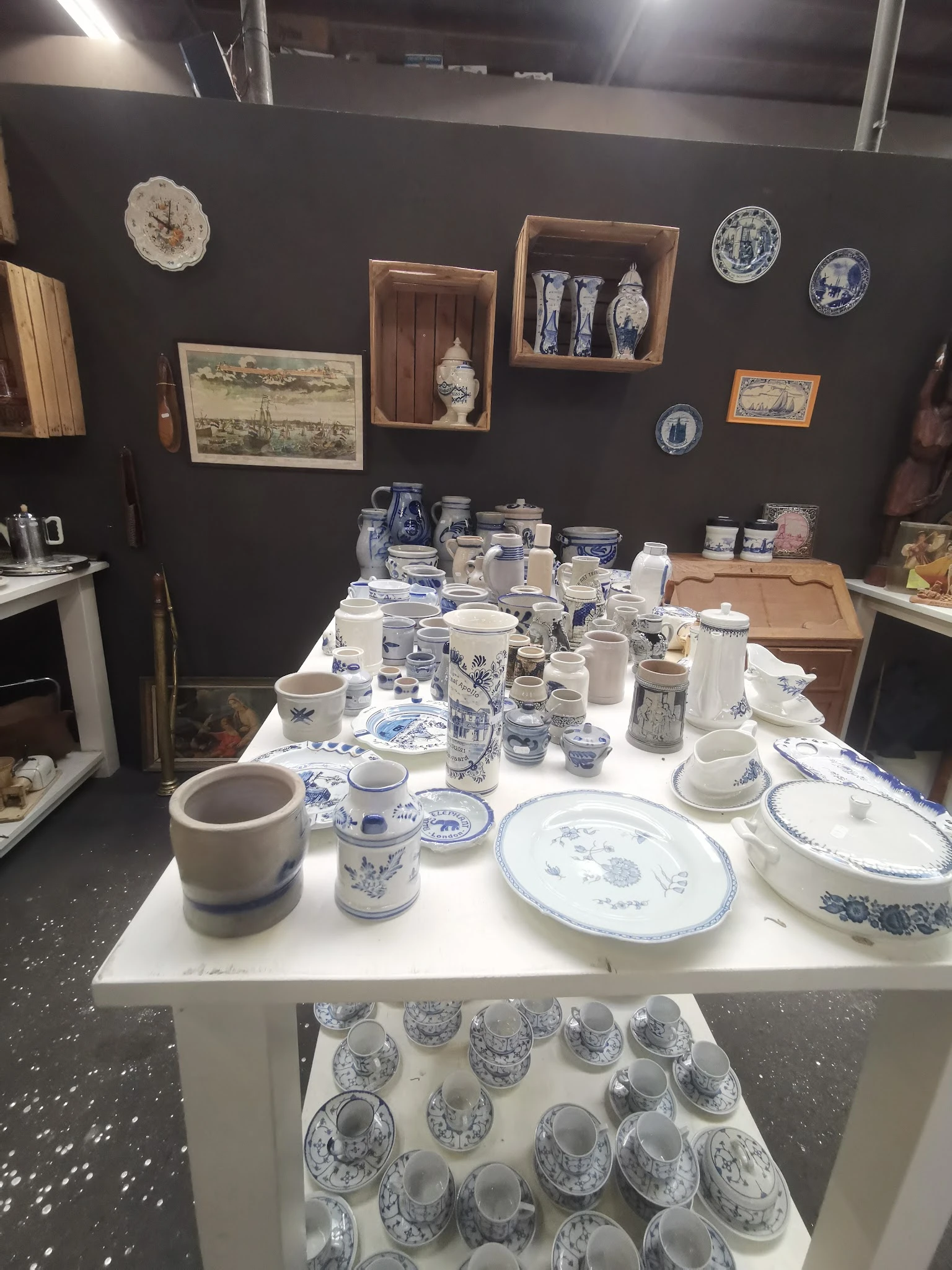 Uitgestalde serviesgoed en huishoudelijke artikelen met blauw-wit porselein op witte tafel