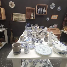 Uitgestalde serviesgoed en huishoudelijke artikelen met blauw-wit porselein op witte tafel