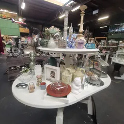 Witte ronde tafels met decoratieve huishoudartikelen: vazen, kaarsenhouders, schalen en verschillende keramische en glazen ob