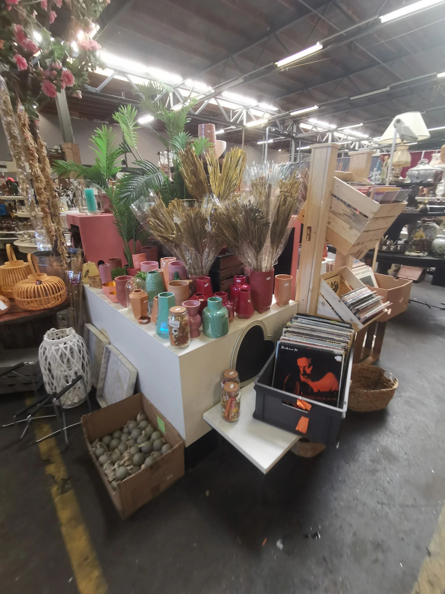 Uitstalling met kaarsen in verschillende kleuren, droogbloemen en decoratieve items op een tafel in de winkel