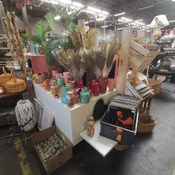 Uitstalling met kaarsen in verschillende kleuren, droogbloemen en decoratieve items op een tafel in de winkel