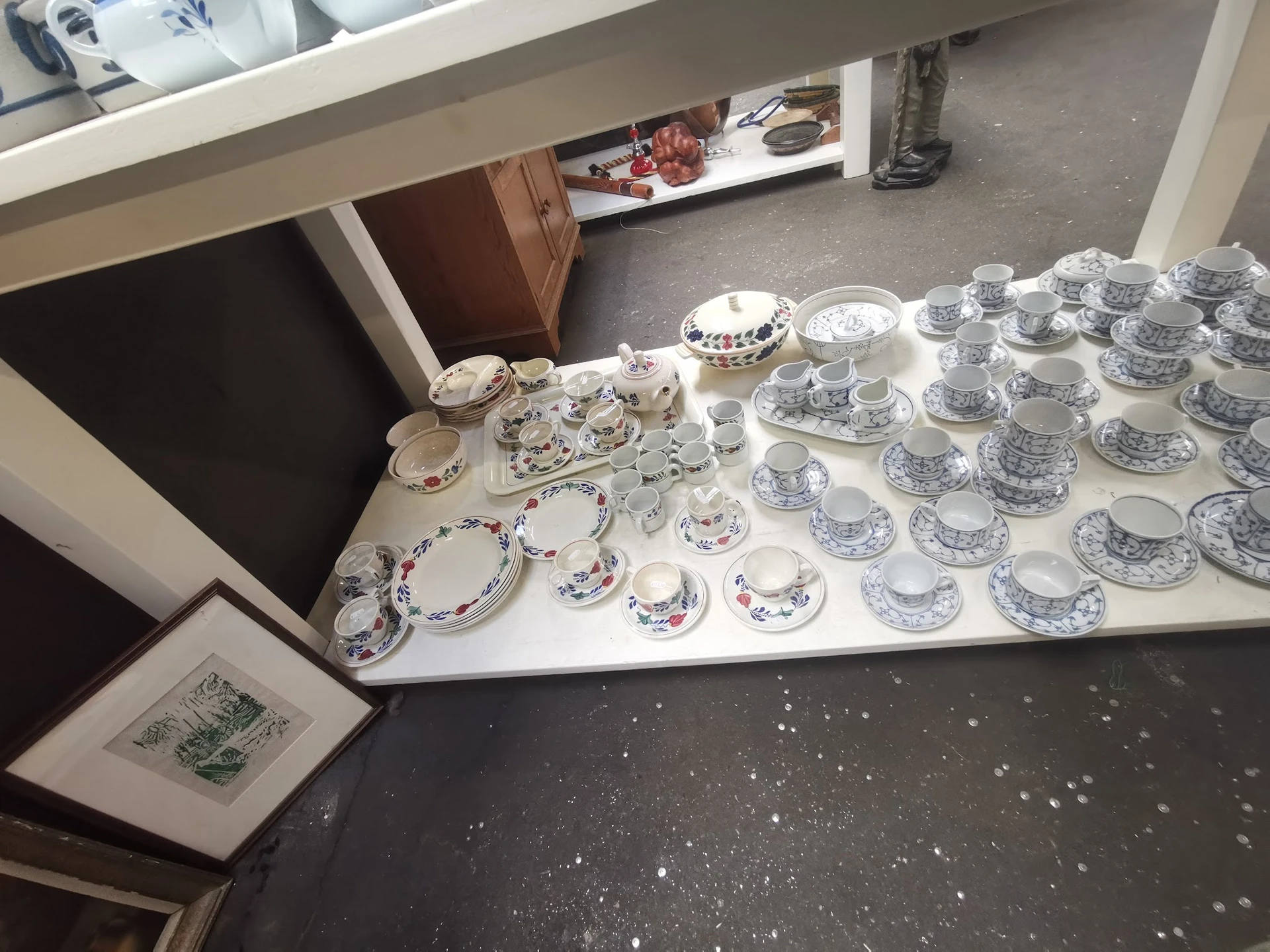 Uitgestalde serviesgoed: kopjes, schotels en borden met blauwe decoratie op witte tafels in de winkel