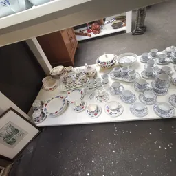 Uitgestalde serviesgoed: kopjes, schotels en borden met blauwe decoratie op witte tafels in de winkel