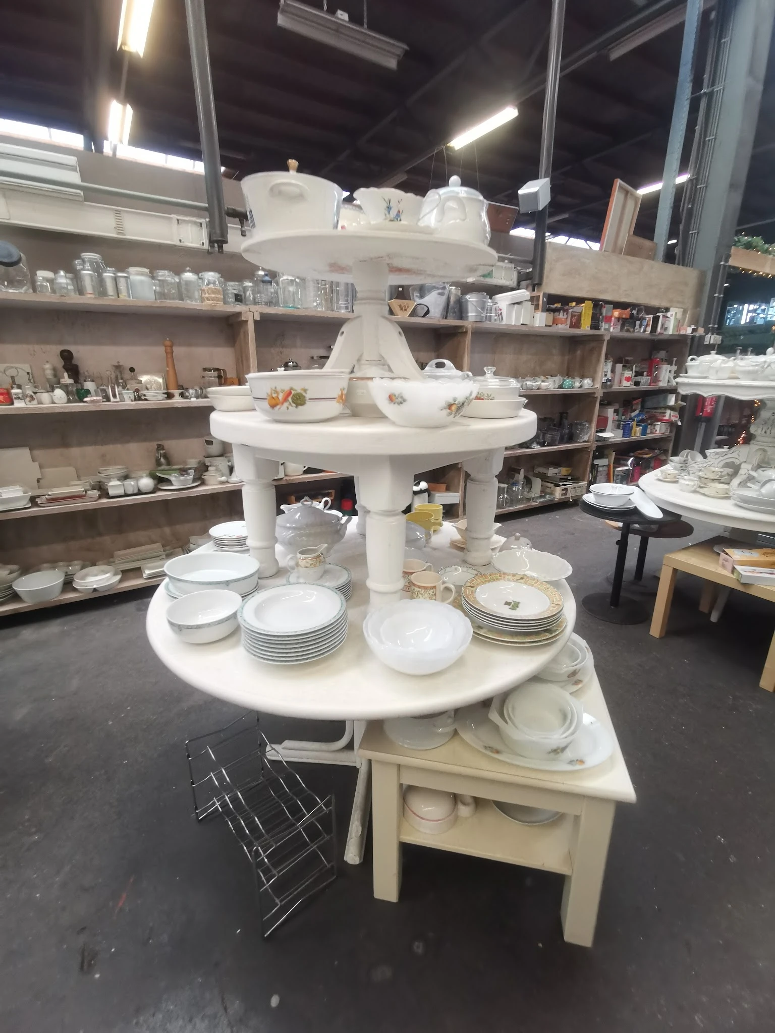 Ronde vitrinekast met porselein servies, borden en schalen uitgestald in kringloopwinkel