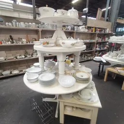Ronde vitrinekast met porselein servies, borden en schalen uitgestald in kringloopwinkel