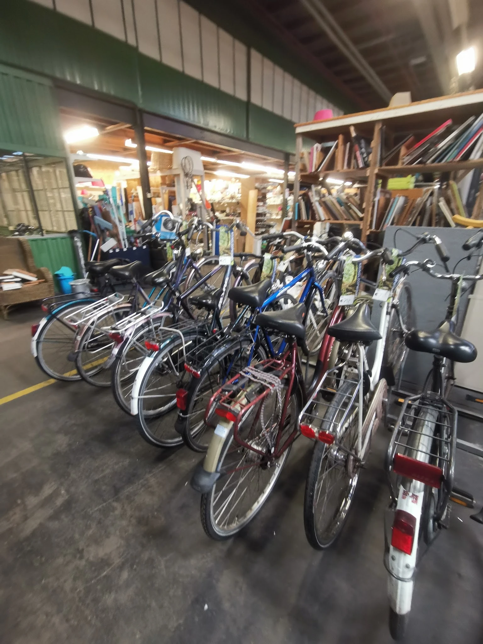 Diverse tweedehands fietsen uitgestald in de winkel, waaronder stadsfietsen en mountainbikes in verschillende kleuren
