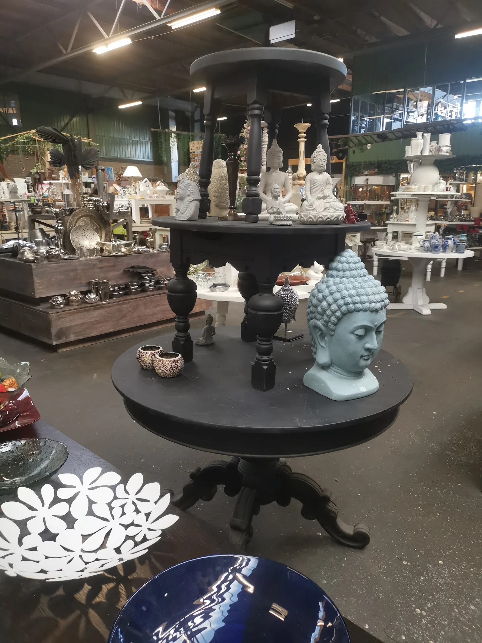 Verschillende boeddhahoofden en decoratieve beelden op zwarte tafels in de winkel