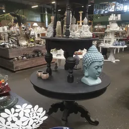 Verschillende boeddhahoofden en decoratieve beelden op zwarte tafels in de winkel