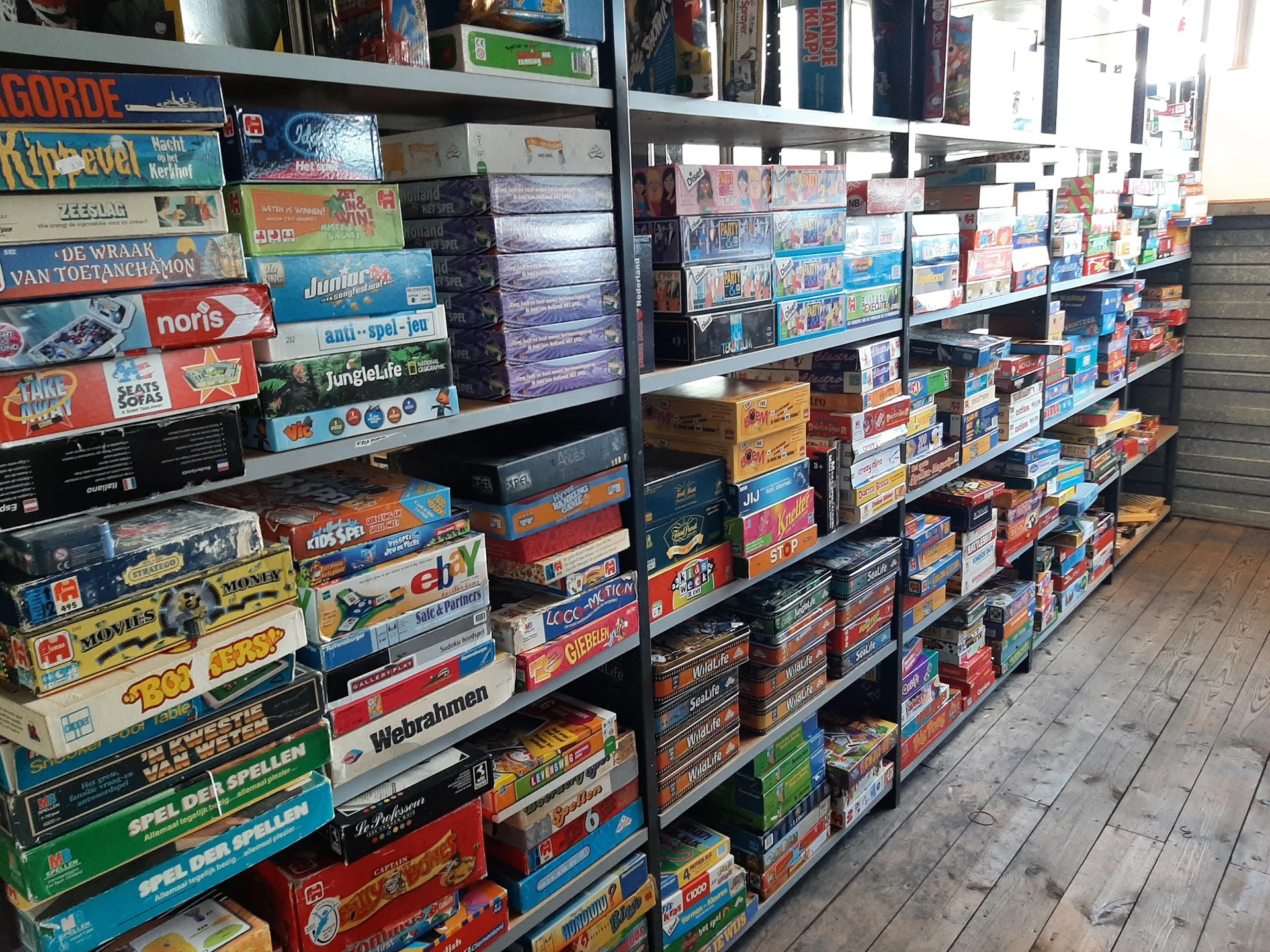 Stellingen volgestapeld met dozen bordspellen en andere tweedehands spellen