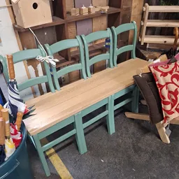 Turquoise houten eetkamerstoel met ladderruggen naast een houten tafel