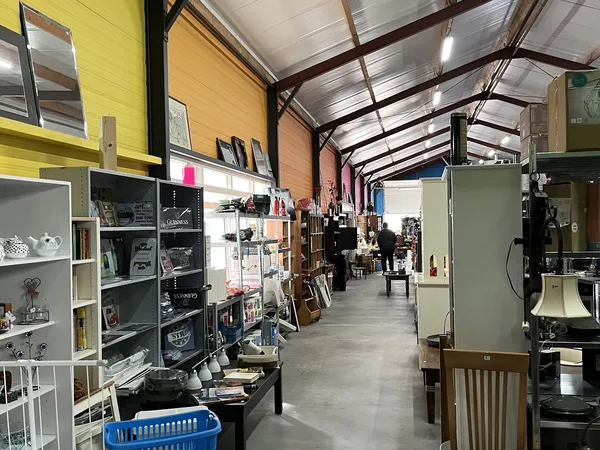 Binnenaanzicht van kringloopwinkel met stellingen, vitrines en diverse tweedehands artikelen langs de winkelvloer