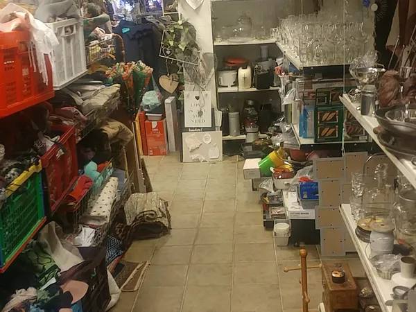 Rommelige winkelvloer met diverse spullen, dozen en artikelen langs de zijkanten en in het midden