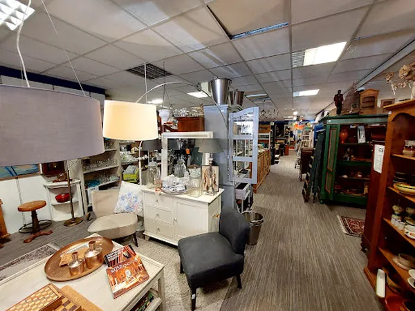 Winkelvloer van kringloopwinkel met diverse meubels, vitrines, stoelen en huishoudartikelen verspreid over het gangpad