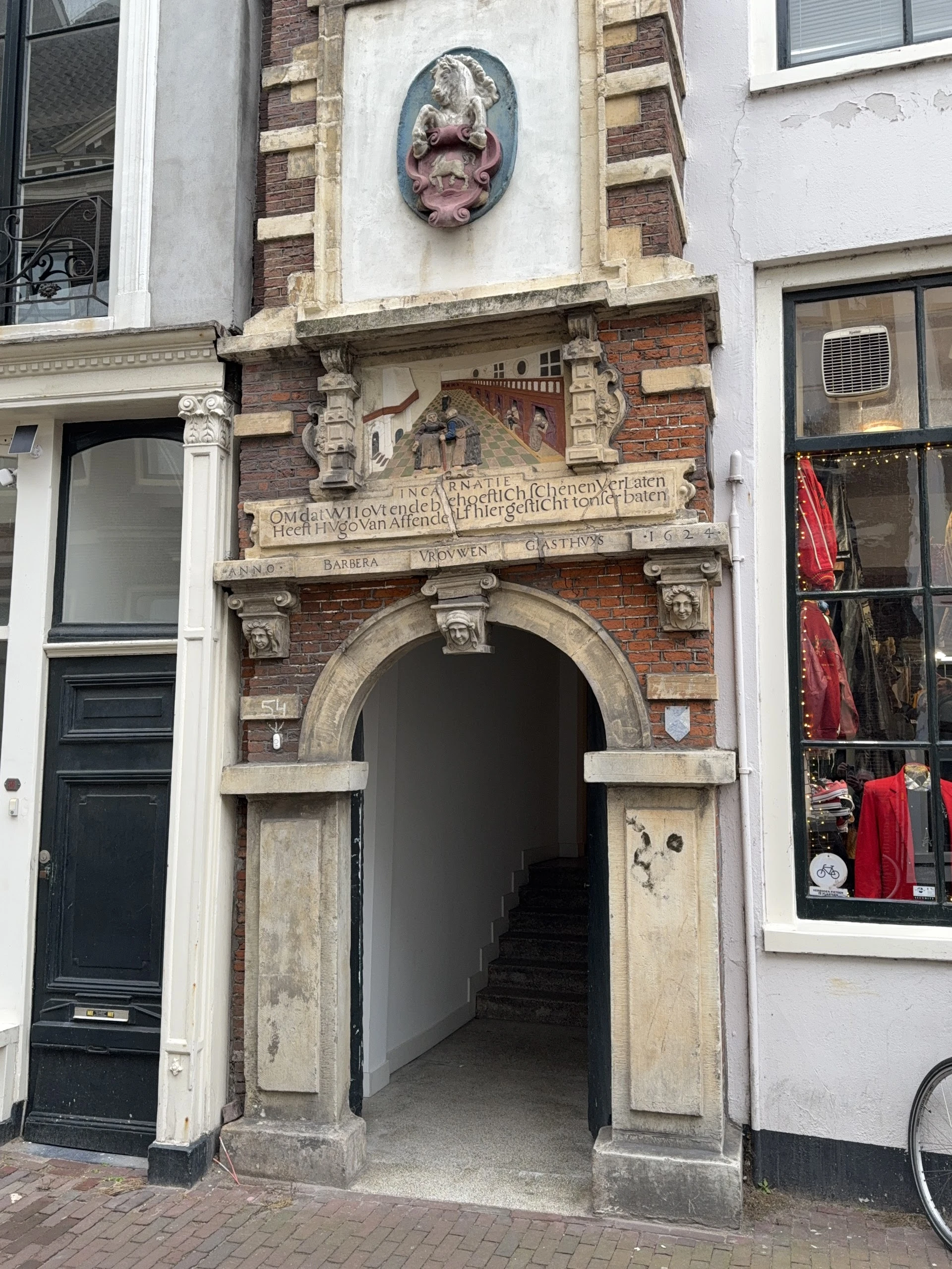 Historische gevel met decoratieve boog en inscriptie, ingangen naar winkelpanden