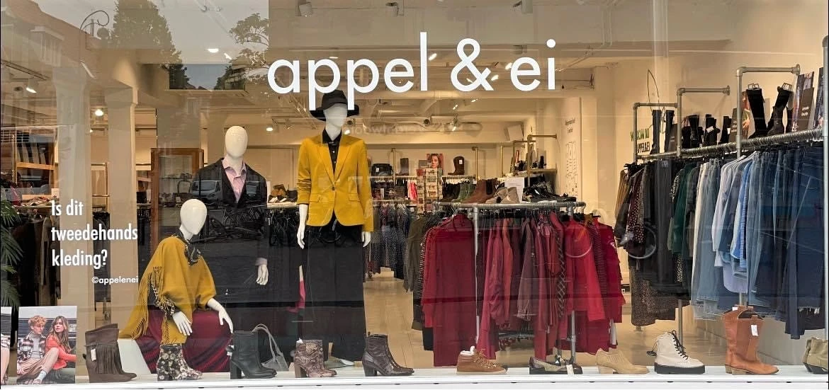 Etalage met mannequins in gele en zwarte blazers, en rekken met rode en zwarte kledingstukken