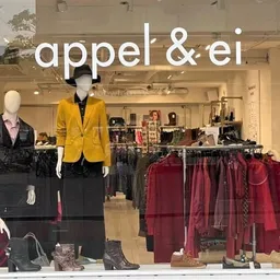 Winkelinterieur met etalagepoppen in kleding, kledingrekken en uitgestalde artikelen in rode en gele tinten