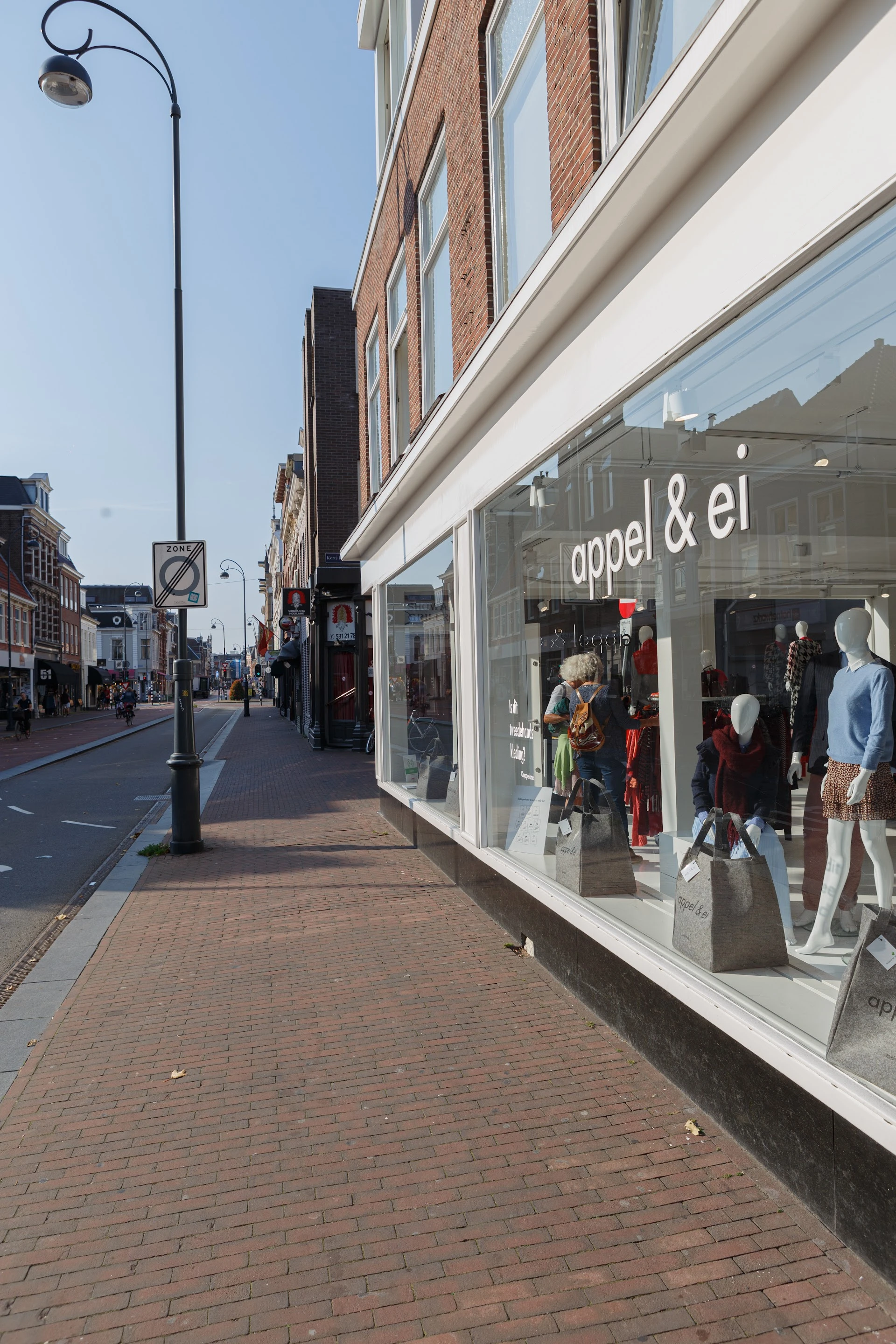 Winkelruit van kledingwinkel 'appel & el' aan straat met etalage met mannequins in kleding