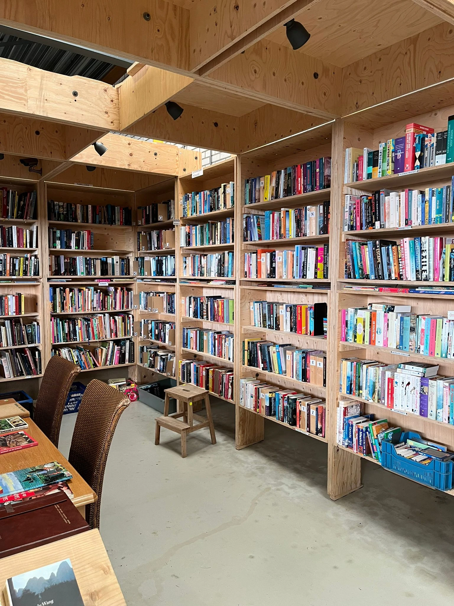 Boekenkasten vol met boeken in een leeshoek met stoelen en houten tafeltje