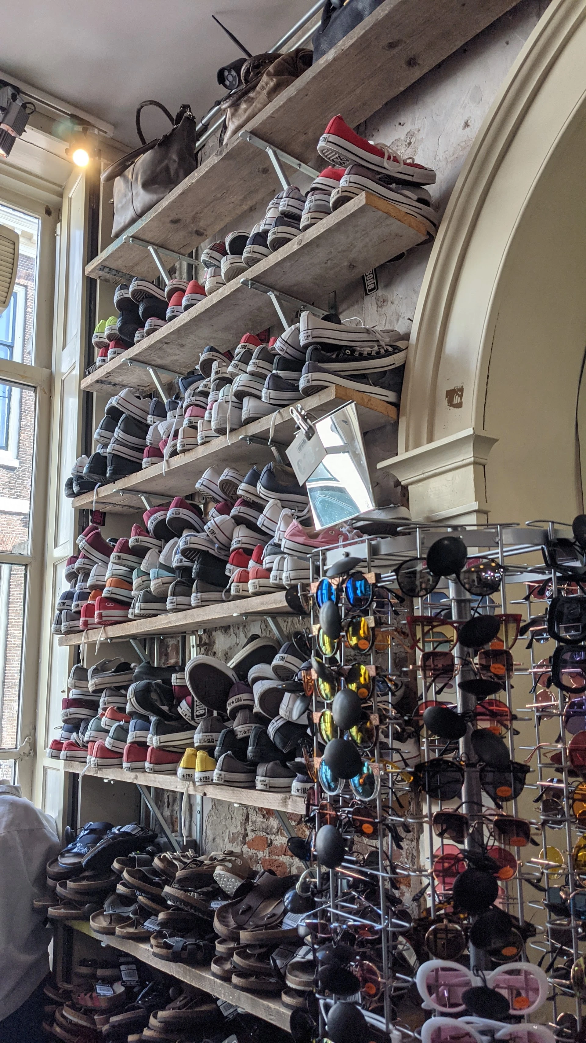 Stellingen vol met gestapelde kleding in verschillende kleuren en patronen, met onderin schoenen op rekken