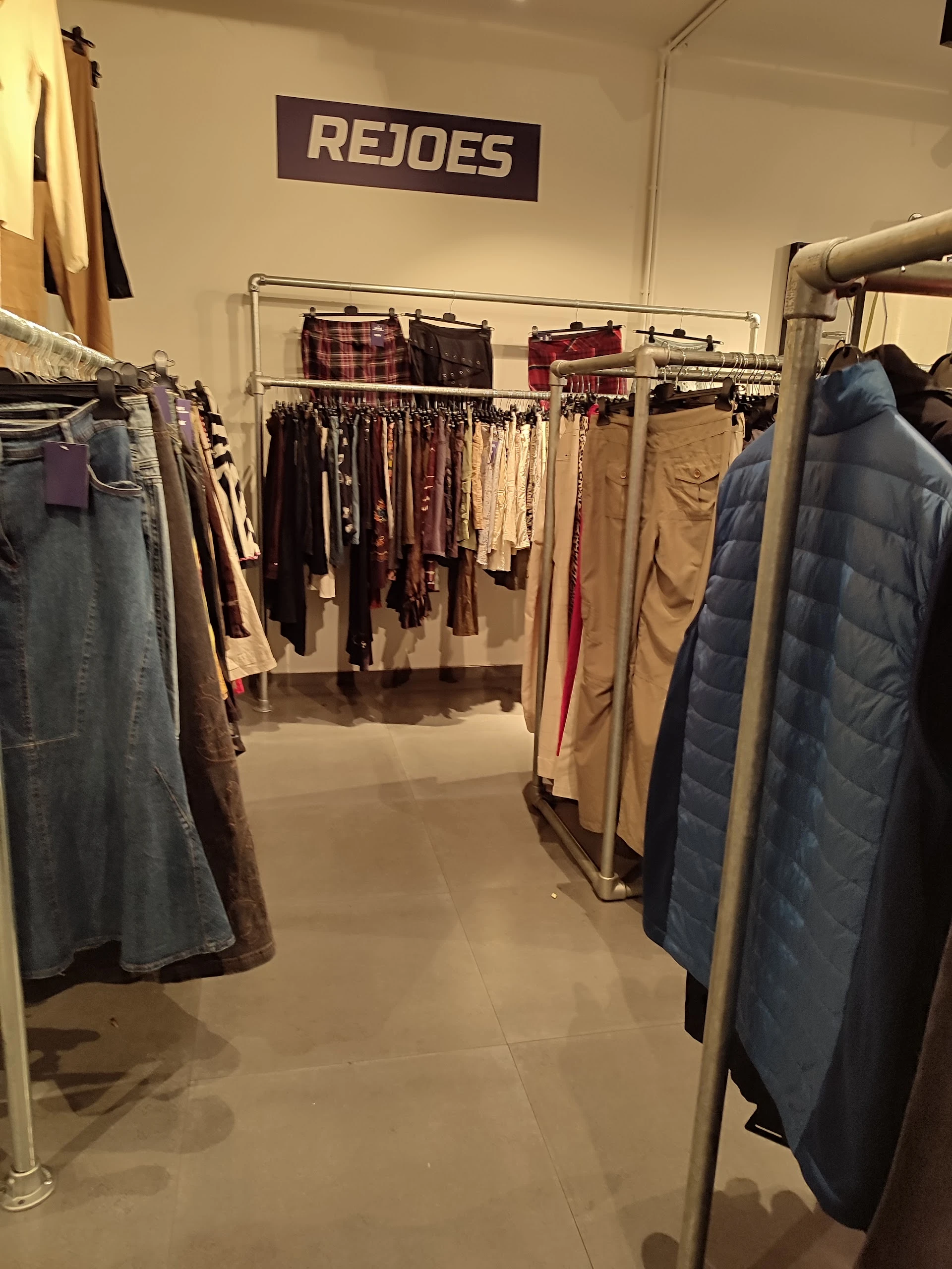 Rekken met tweedehands kleding, waaronder jassen, broeken en jurken in verschillende kleuren