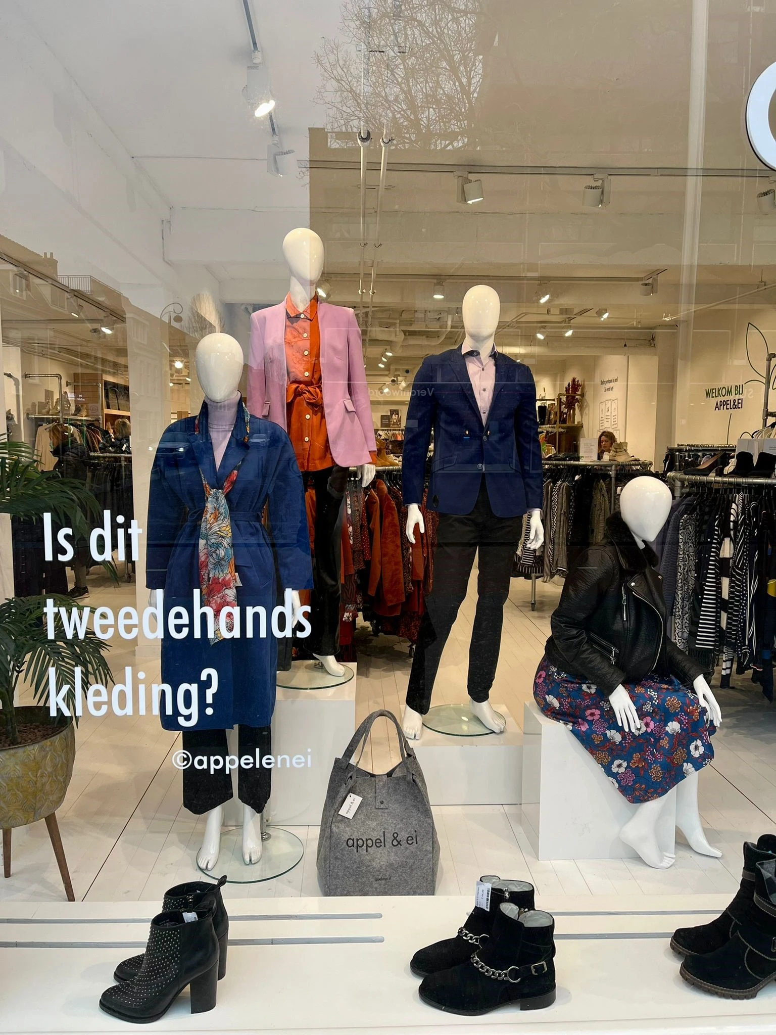 Etalage met mannequins in tweedehands kleding: blazers, jasjes en broeken in verschillende kleuren en stijlen