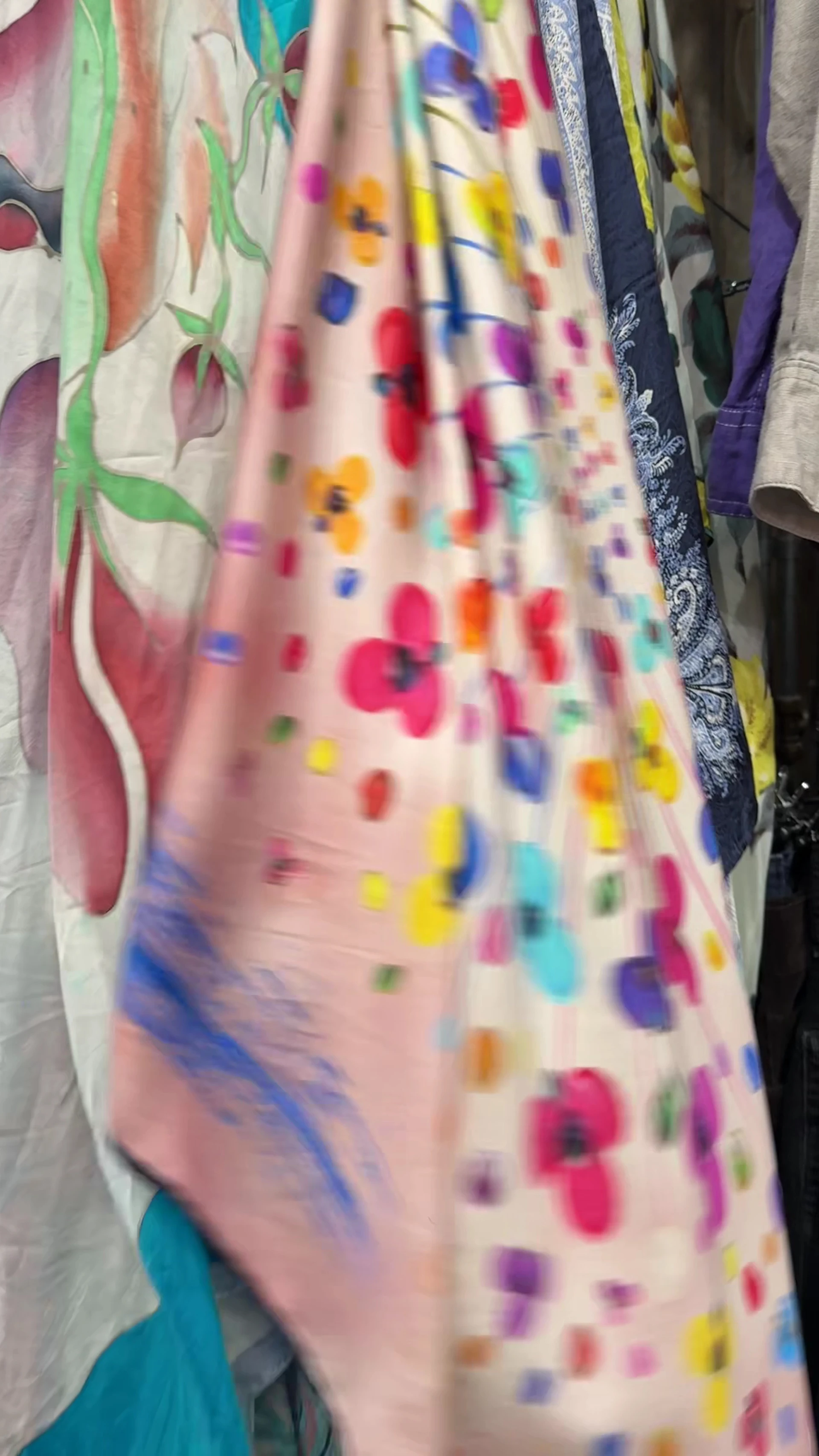 Roze kinderkledingstuk met gekleurde bloemenprint, hangend aan kledinrek