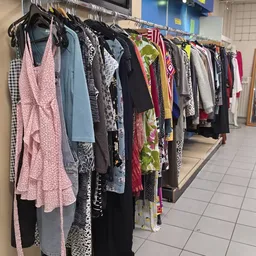 Rekken met tweedehands dameskleding in verschillende kleuren en patronen