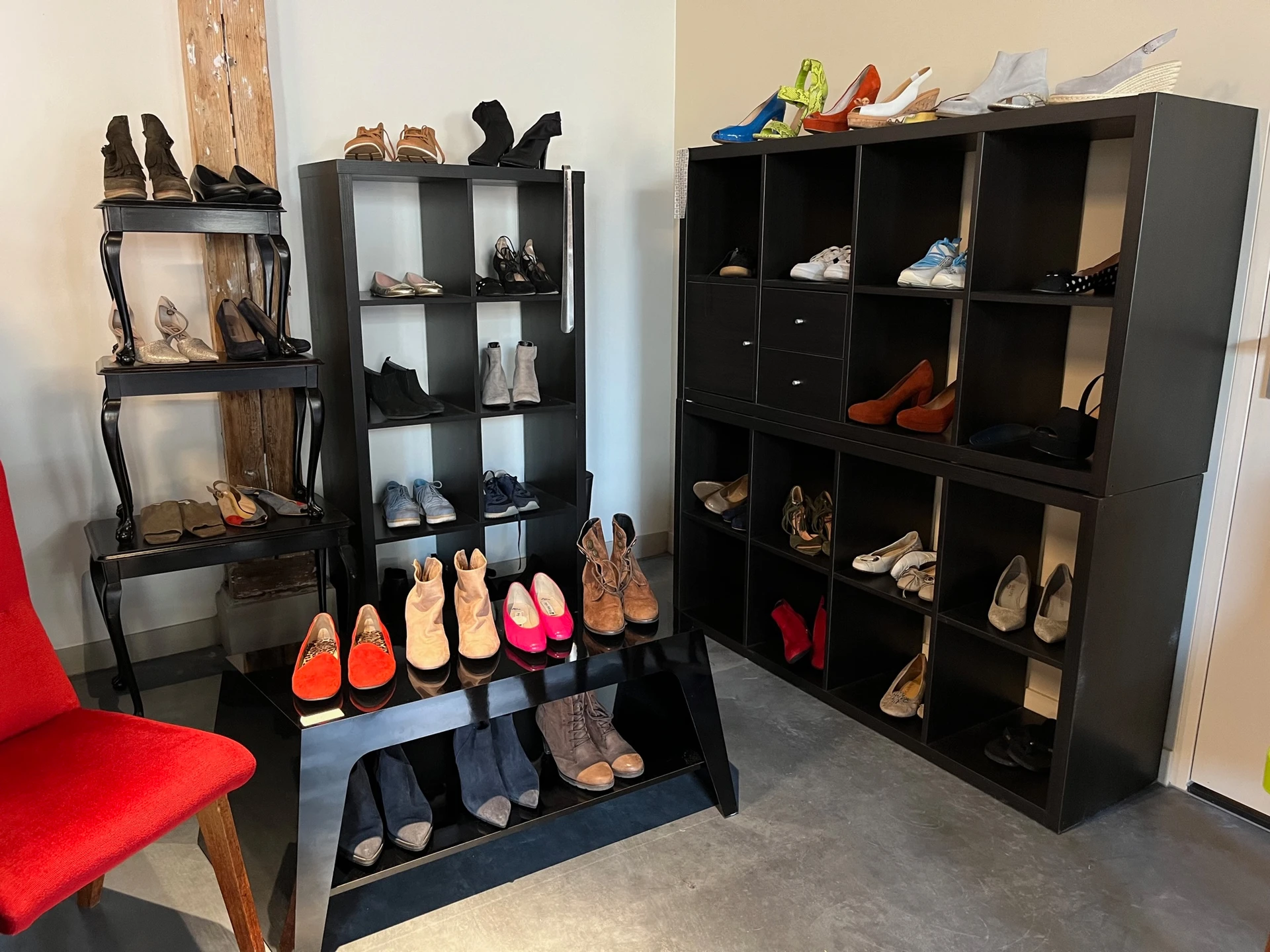 Uitgestalde verzameling tweedehands schoenen en laarzen op zwarte stellingen en in een vitrinekast