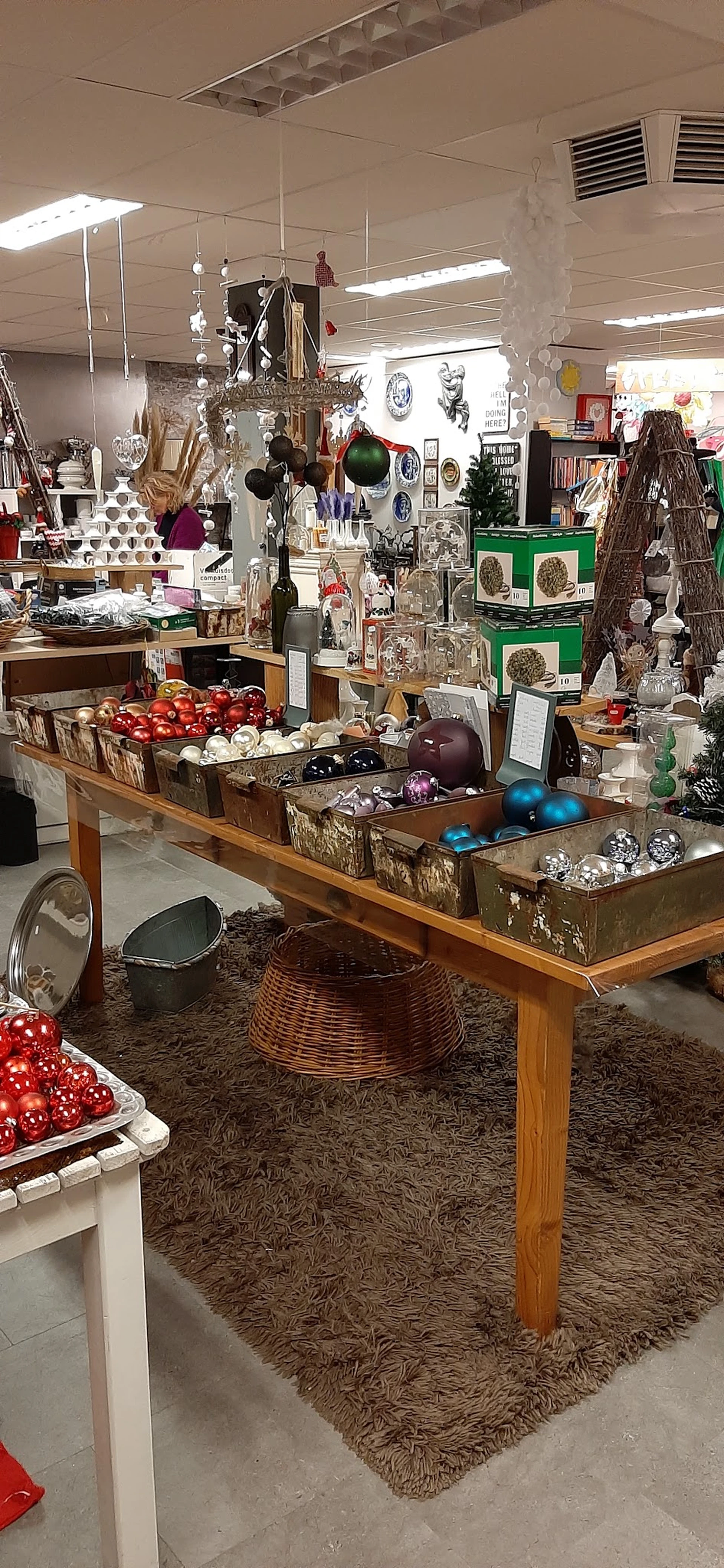 Houten tafel met uitgestalde kerstballen in verschillende kleuren en glazen decoratieartikelen