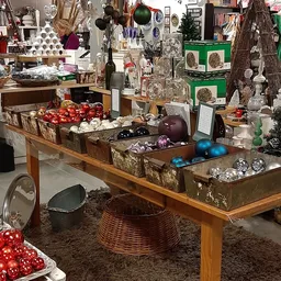 Houten tafel met uitgestalde kerstballen in verschillende kleuren en glazen decoratieartikelen
