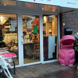 Winkelfront met glazen deuren en roze decoratieve objecten buiten
