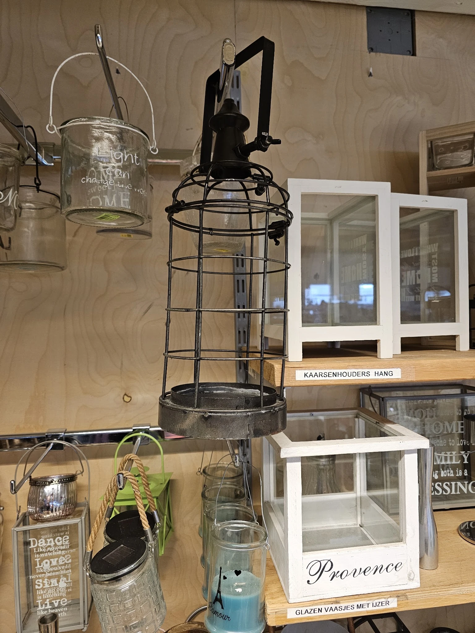 Tweedehands huishoudelijke artikelen: zwarte hanglamp, glazen potten, witte kasten en decoratieve items op stellingen