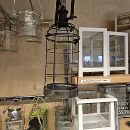 Tweedehands huishoudelijke artikelen: zwarte hanglamp, glazen potten, witte kasten en decoratieve items op stellingen