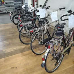 Rij tweedehands fietsen met rode reflectoren en zwarte zadels uitgestald in de winkel