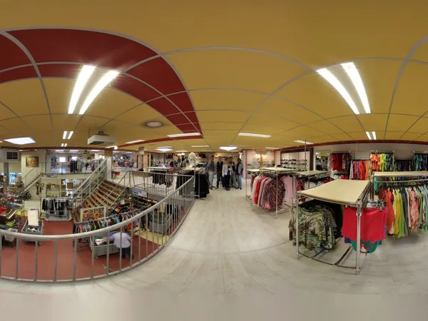 Winkelvloer van kringloopwinkel met kleding op rekken, trappen en winkelafdelingen onder rode en grijze plafondpanelen met ve