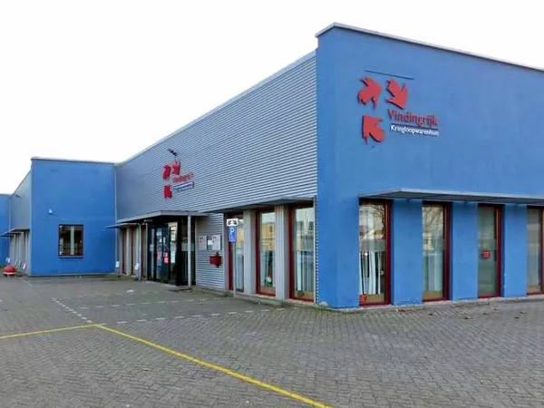 Blauwe gevel van kringloopwarenhuis Vindingrijk met rode letters, ingangsdeuren en ramen