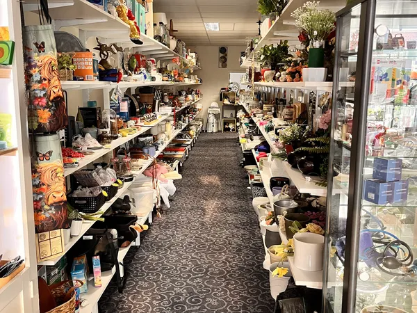 Winkelgang met stellingen vol spullen, bloemen en decoratieartikelen langs beide zijden