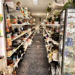 Winkelgang met stellingen vol spullen, bloemen en decoratieartikelen langs beide zijden