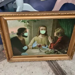 Goudkleurig ingelijst schilderij met drie figuren in medische maskers rond een tafel
