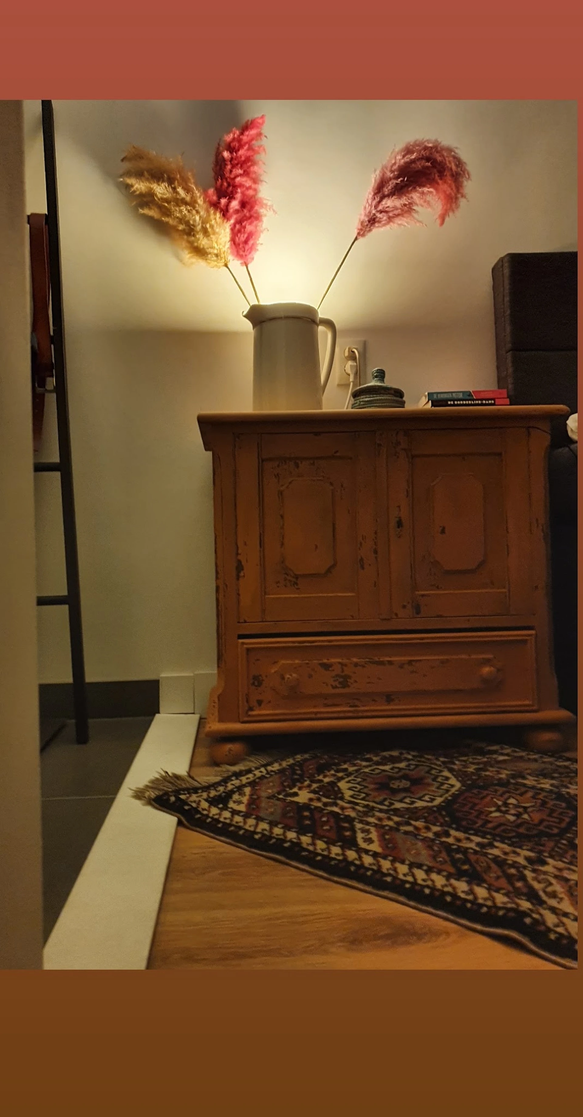 Houten kast met twee deuren en een lade, op een bed in een kamer
