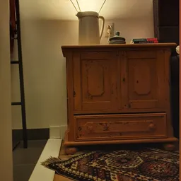 Houten kast met twee deuren en een lade, op een bed in een kamer