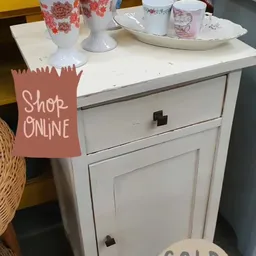 Witte kast met laden en kastdeuren, op het blad serviesgoed en decoratiestukken
