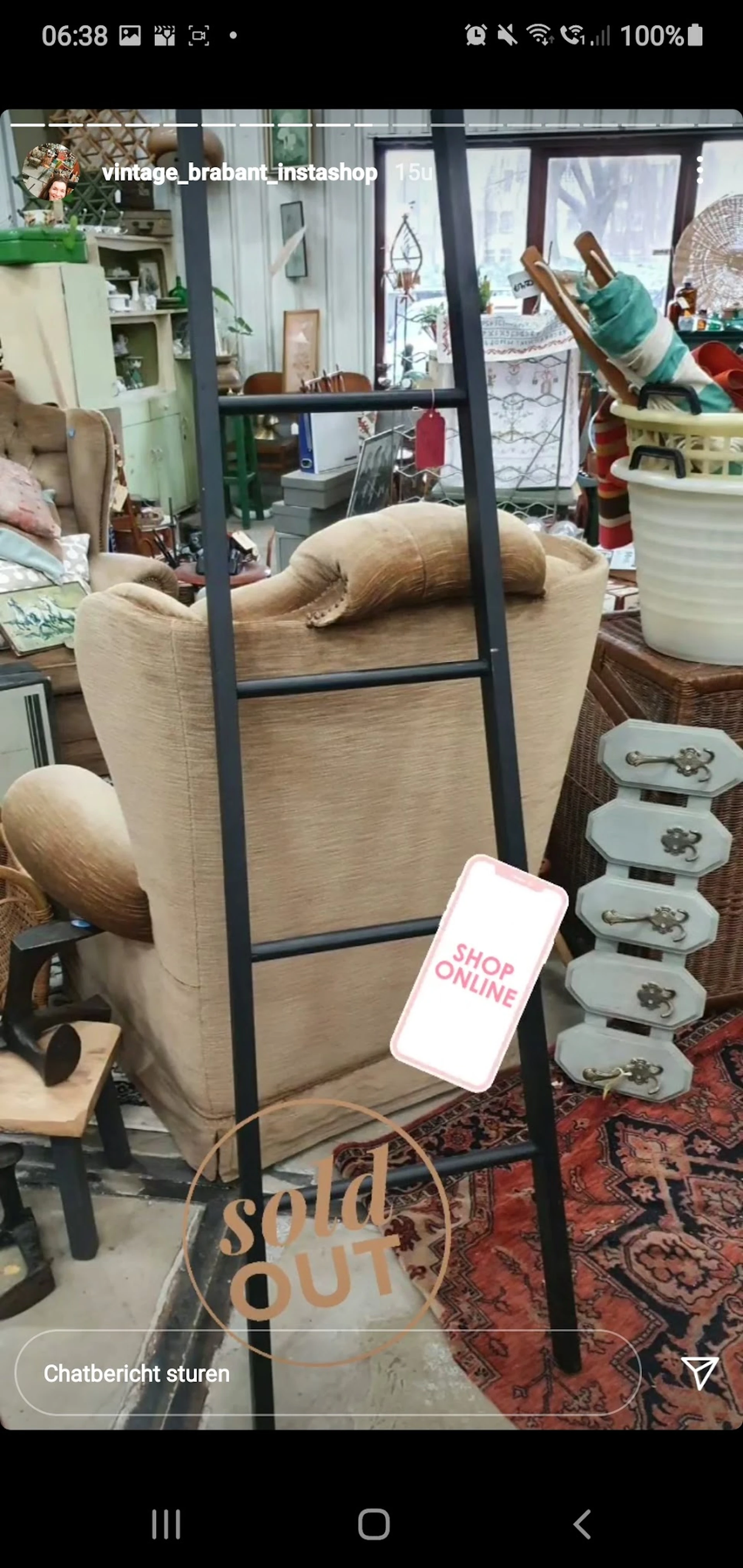 Beige fauteuil met zwart frame en houten armleuningen naast serviesgoed en andere meubels in de winkel