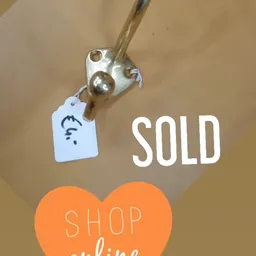 Vintage zilveren bel aan sleutelhanger met prijskaartje, tegen beige achtergrond