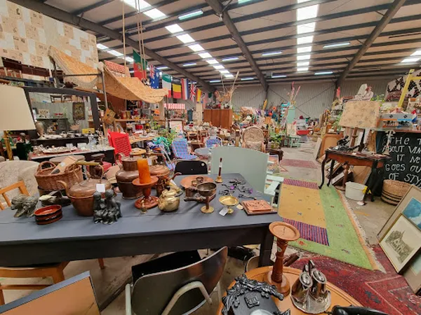 Binnenaanzicht van kringloopwinkel met tafels, stoelen en diverse tweedehands spullen