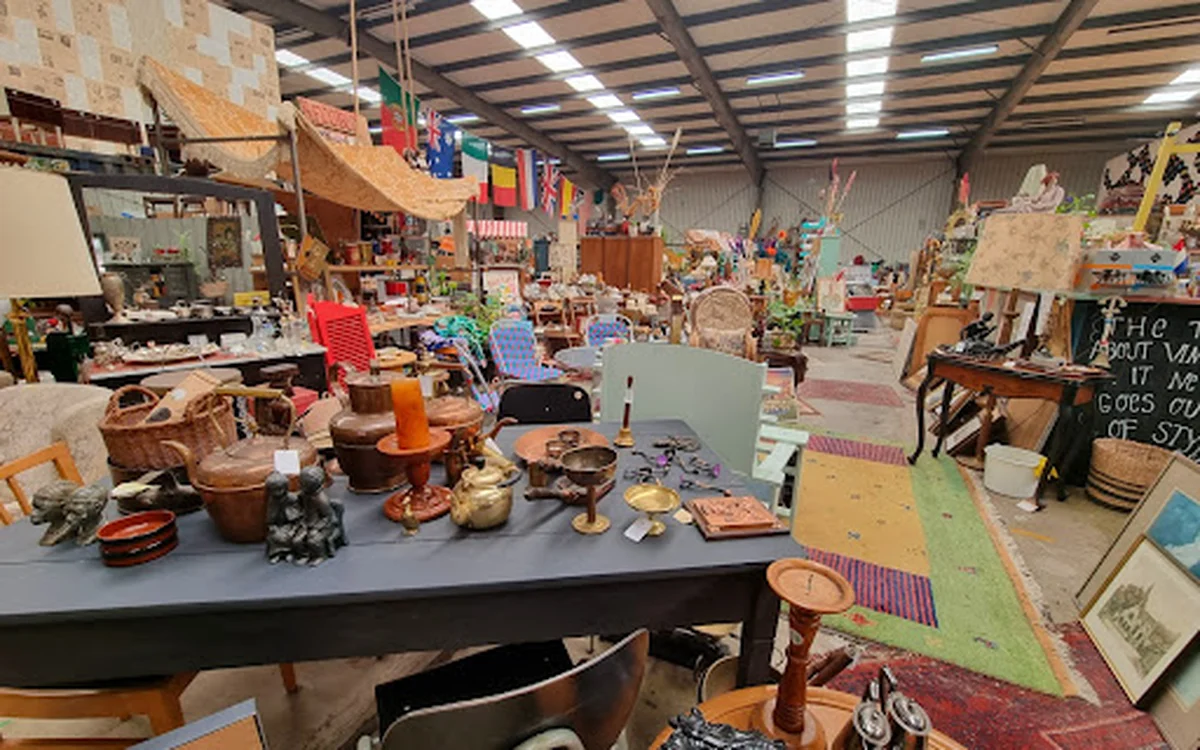 Binnenaanzicht van kringloopwinkel met tafels, stoelen en diverse tweedehands spullen
