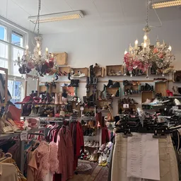 Winkelinterieur met uitgestalde vintage kleding, accessoires en decoratie onder kristallen kroonluchters