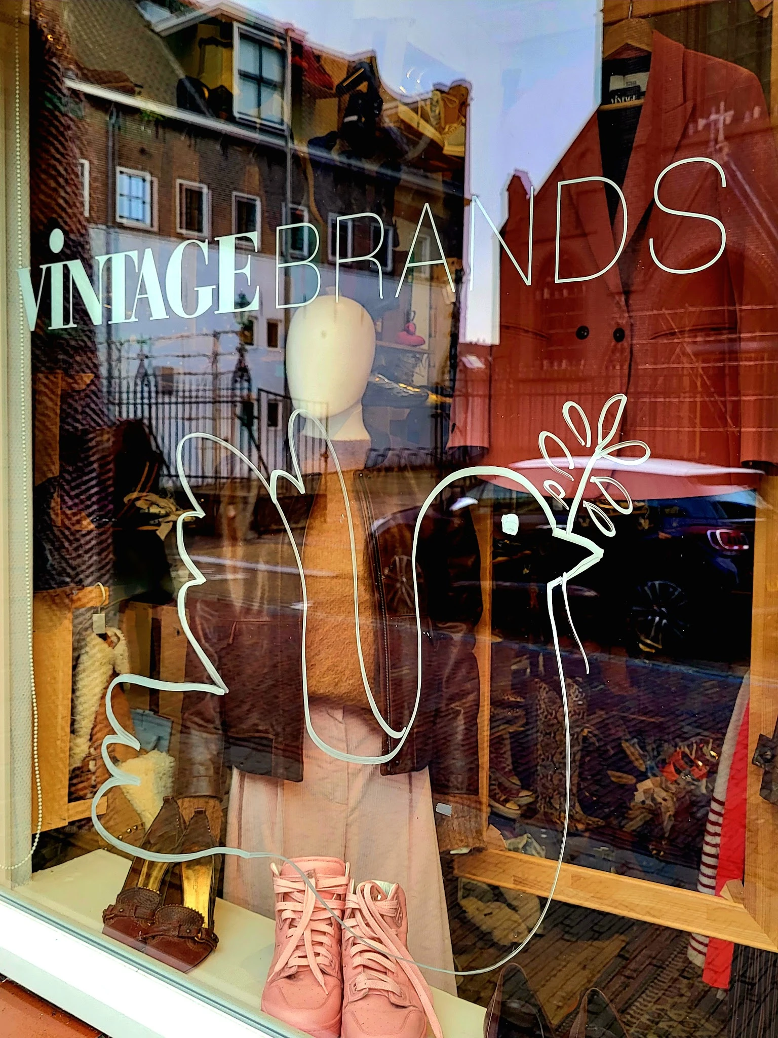 Etalageruit met winkelmanequin en decoratieve tekening, reflecties van straat zichtbaar