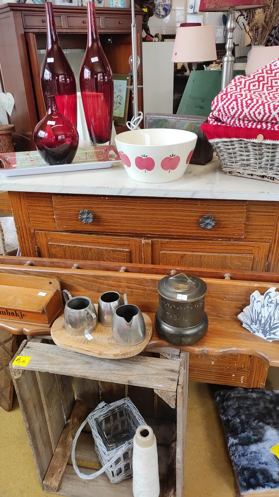 Houten display met vintage servies- en huishoudartikelen, inclusief zilveren kannen en decoratieve pot